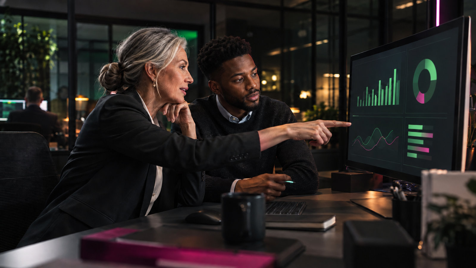 Two bank analysts discussing consolidated charts on a large screen