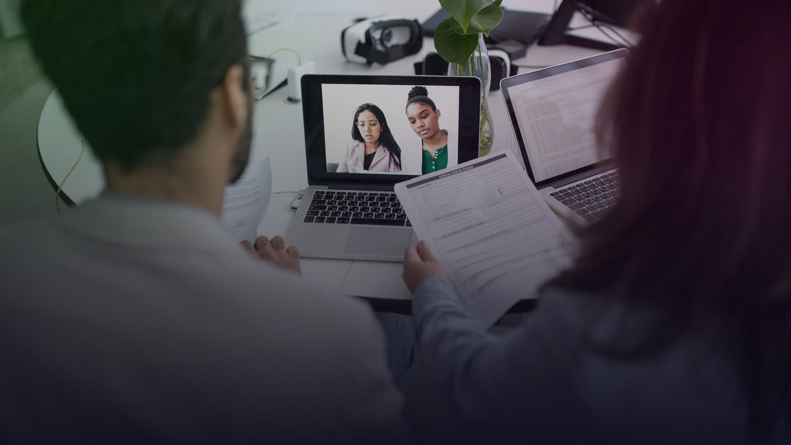 Zwei Fachkräfte führen ein virtuelles Bewerbungsgespräch über einen Laptop.